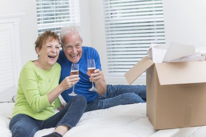 Senior couple moving house, celebrating with champagne