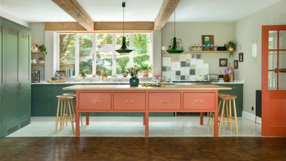 A large open plan kitchen, featuring green kitchen cabinets and a bright orange kitchen island