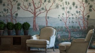 room with forest-themed wallpaper and off-white armchairs