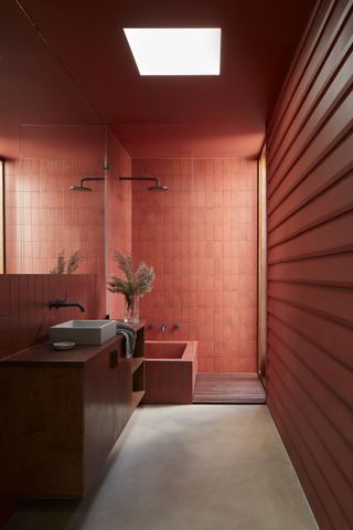 A red tiled bathroom with a natural wood cabinet