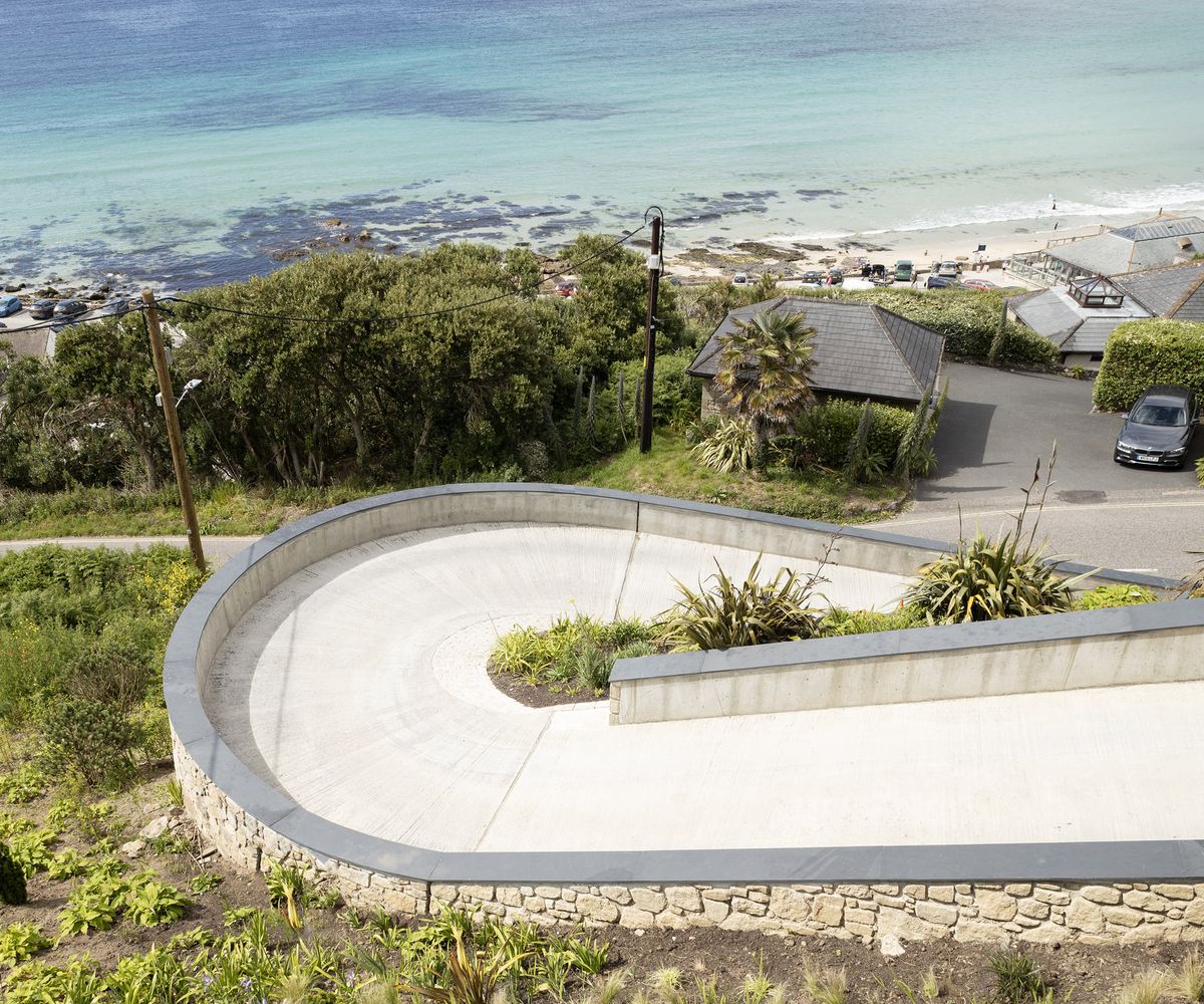 A long winding driveway leading up to a new build home from a coastal path