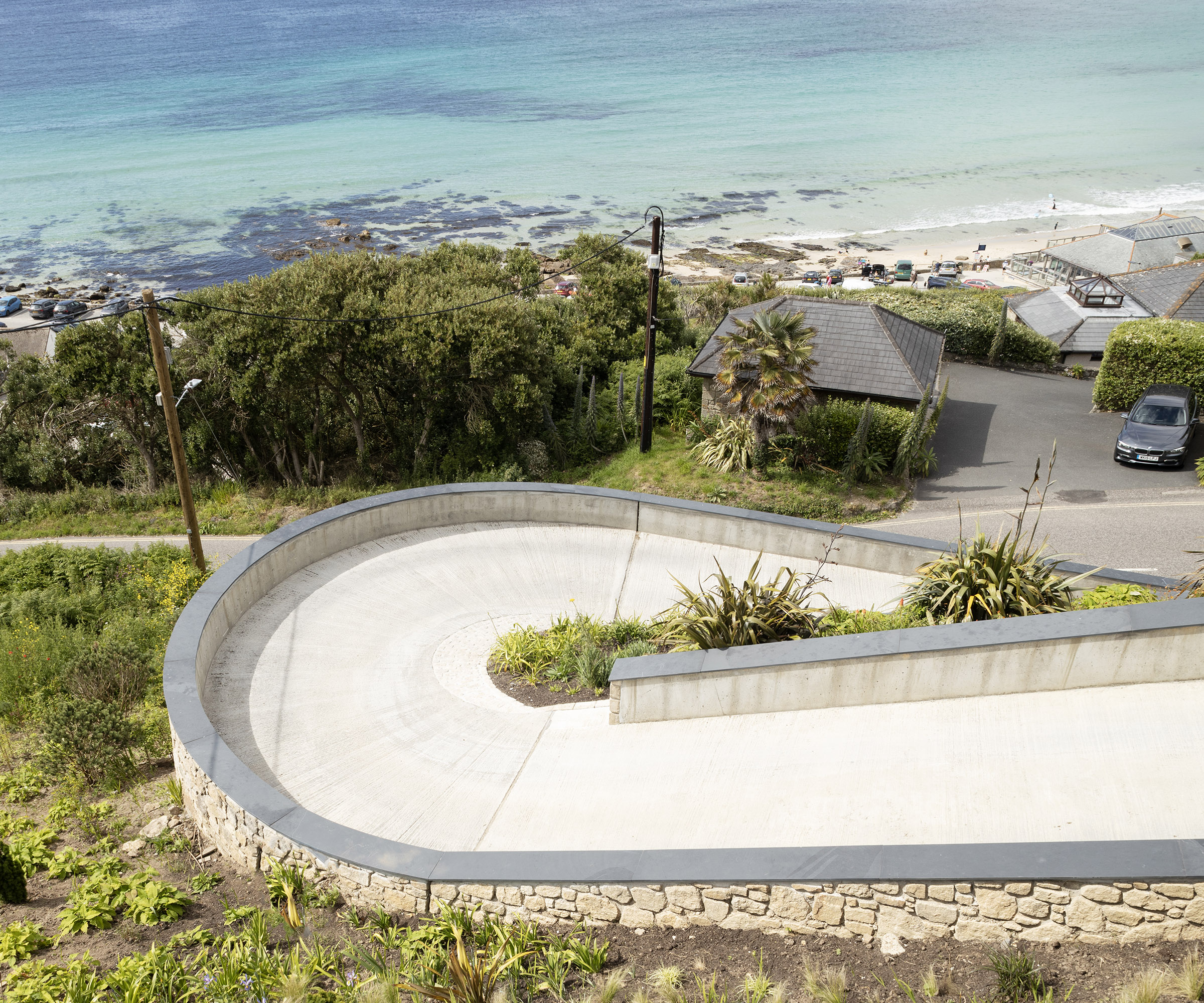 A long winding driveway leading up to a new build home from a coastal path
