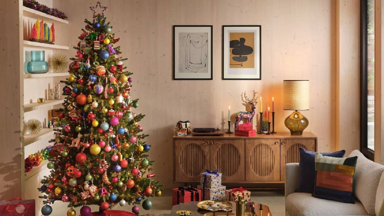 A modern living room with a large Christmas tree decorated in colourful baubles from John Lewis.