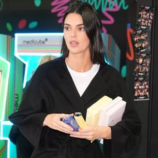 Kendall jenner wears a white tee and a black coat.
