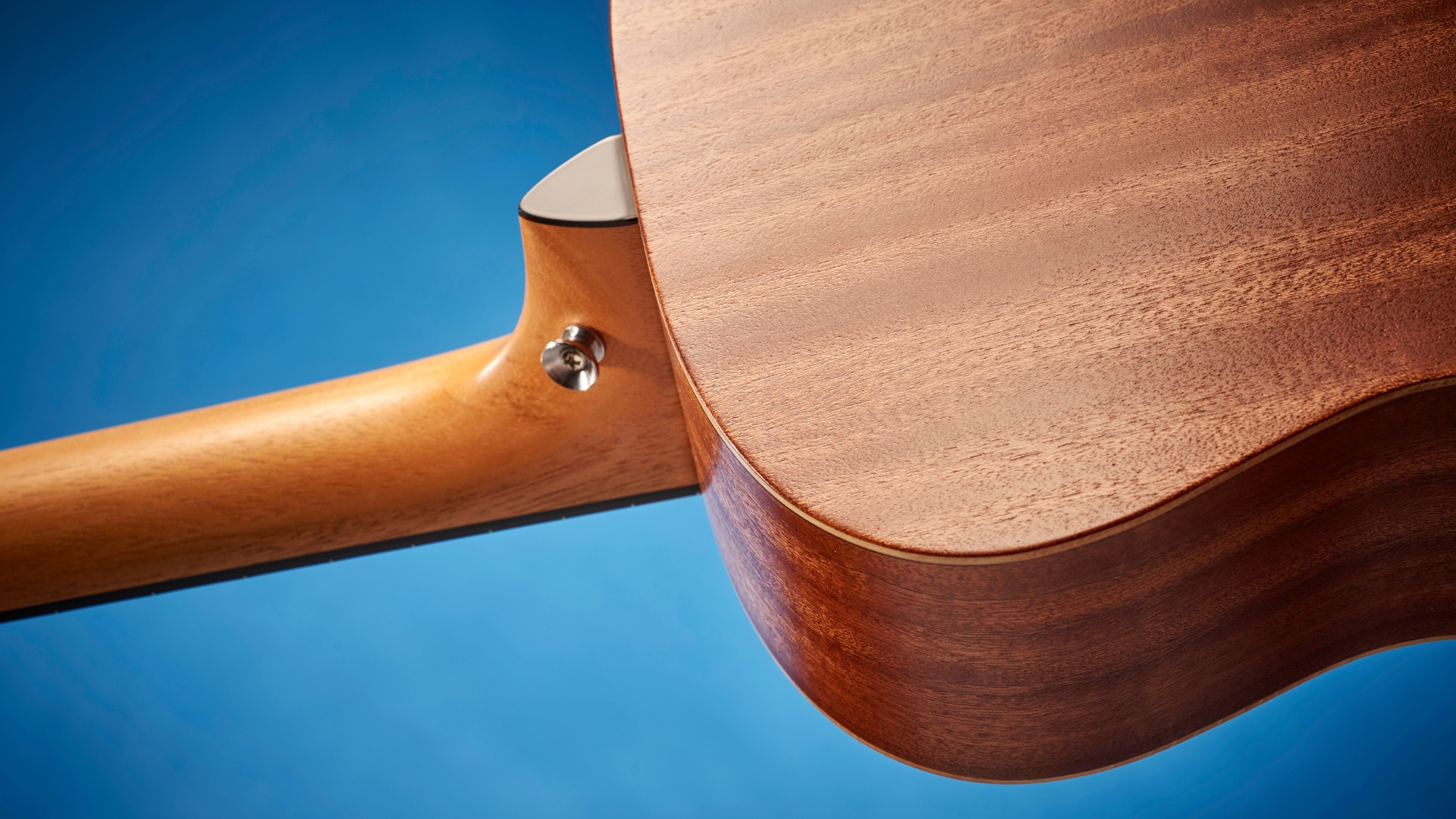 The neck joint of an acoustic guitar a on a blue background