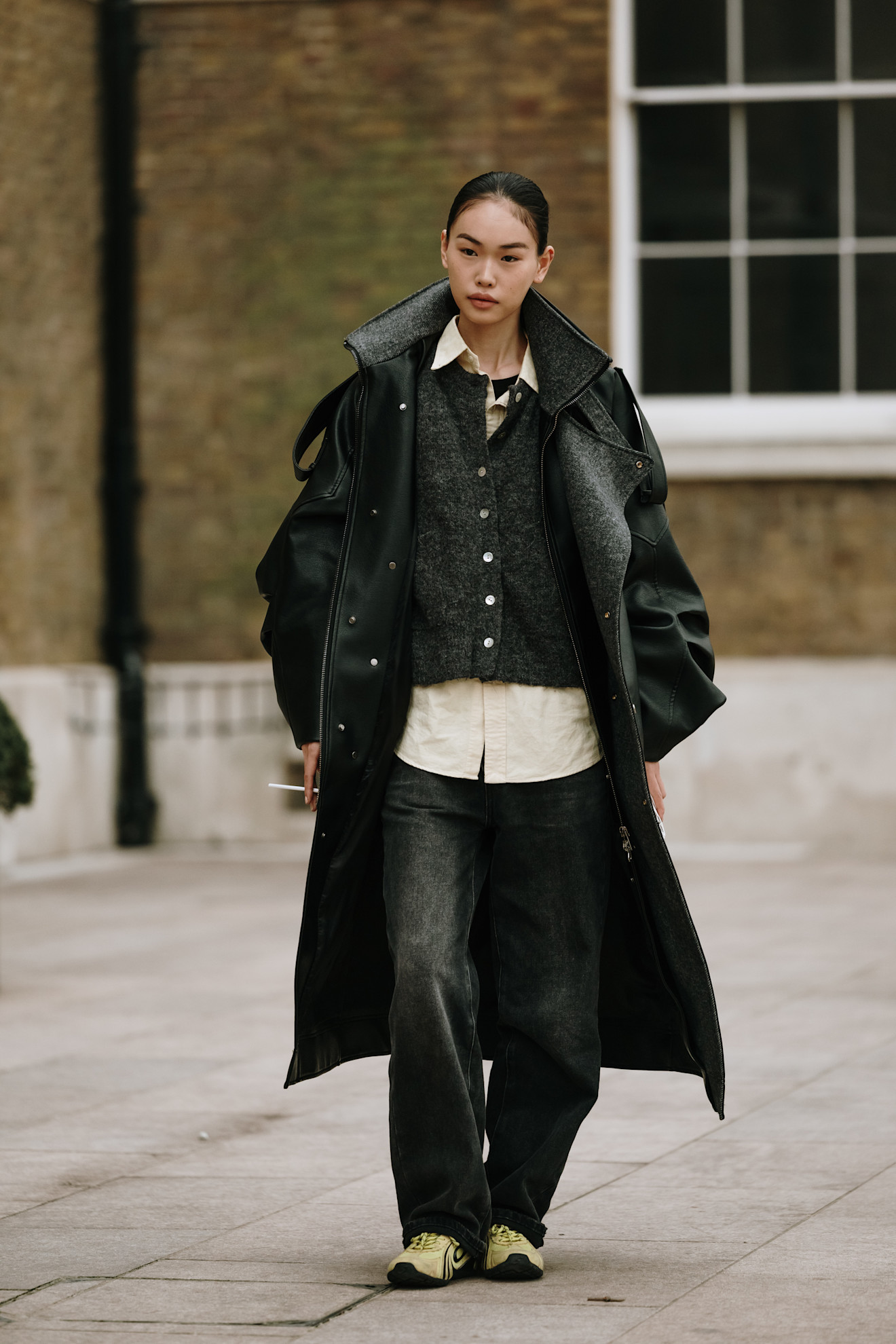 woman wearing a leather coat, a cardigan, pants, and sneakers