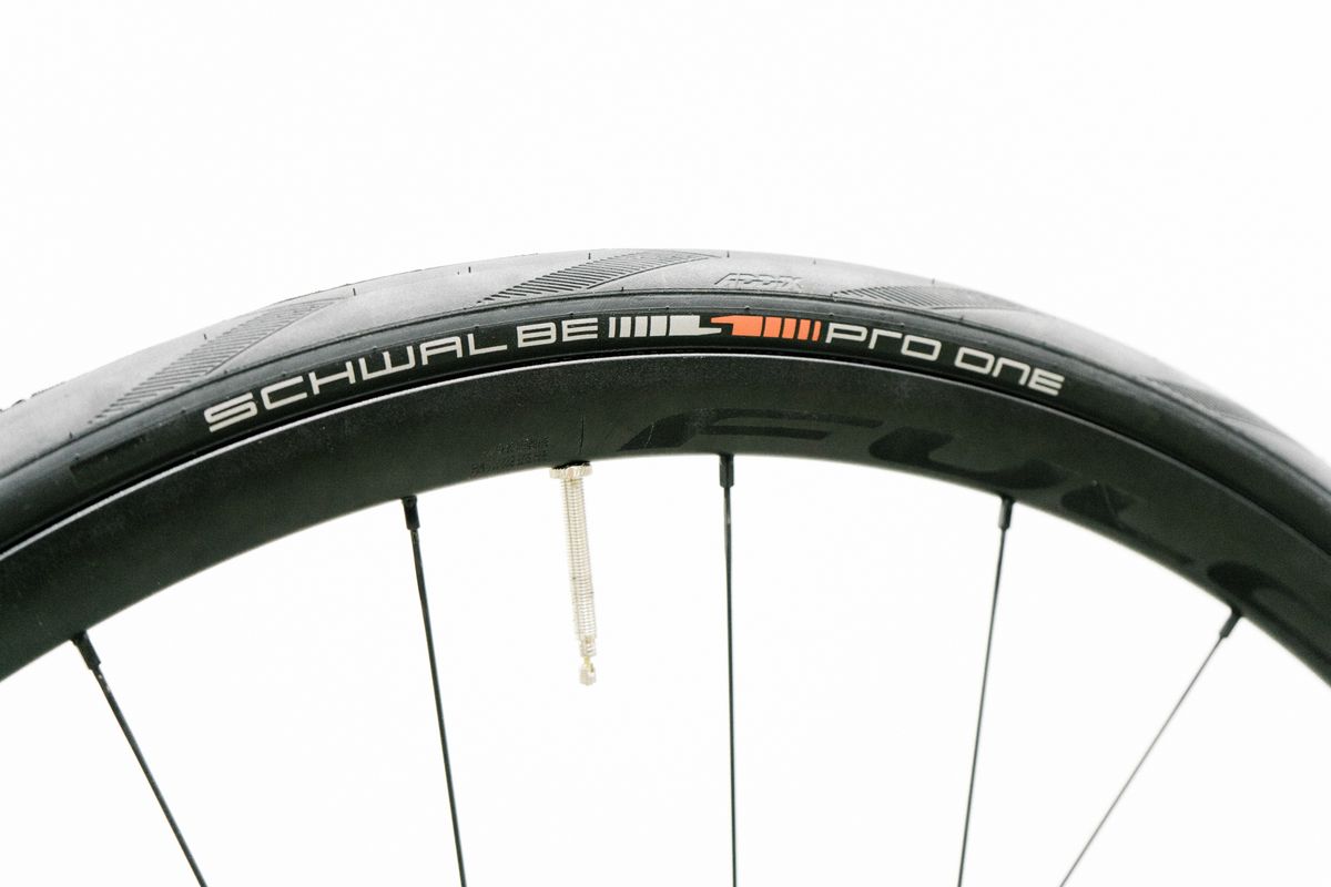 An aero road wheel stands against a white wall