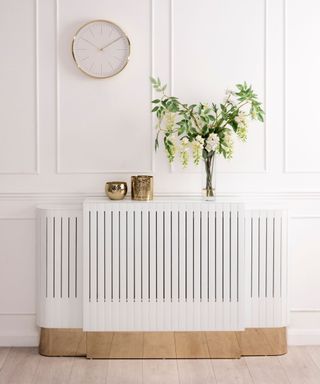 A white radiator cover with a plant and candles on top of it