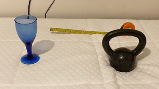 A wine glass, a weight and a tape measure on the Nectar Essential Hybrid Mattress