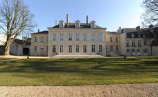 A large chateau which has been turned into a hotel. It sits behind a lawn with a tree