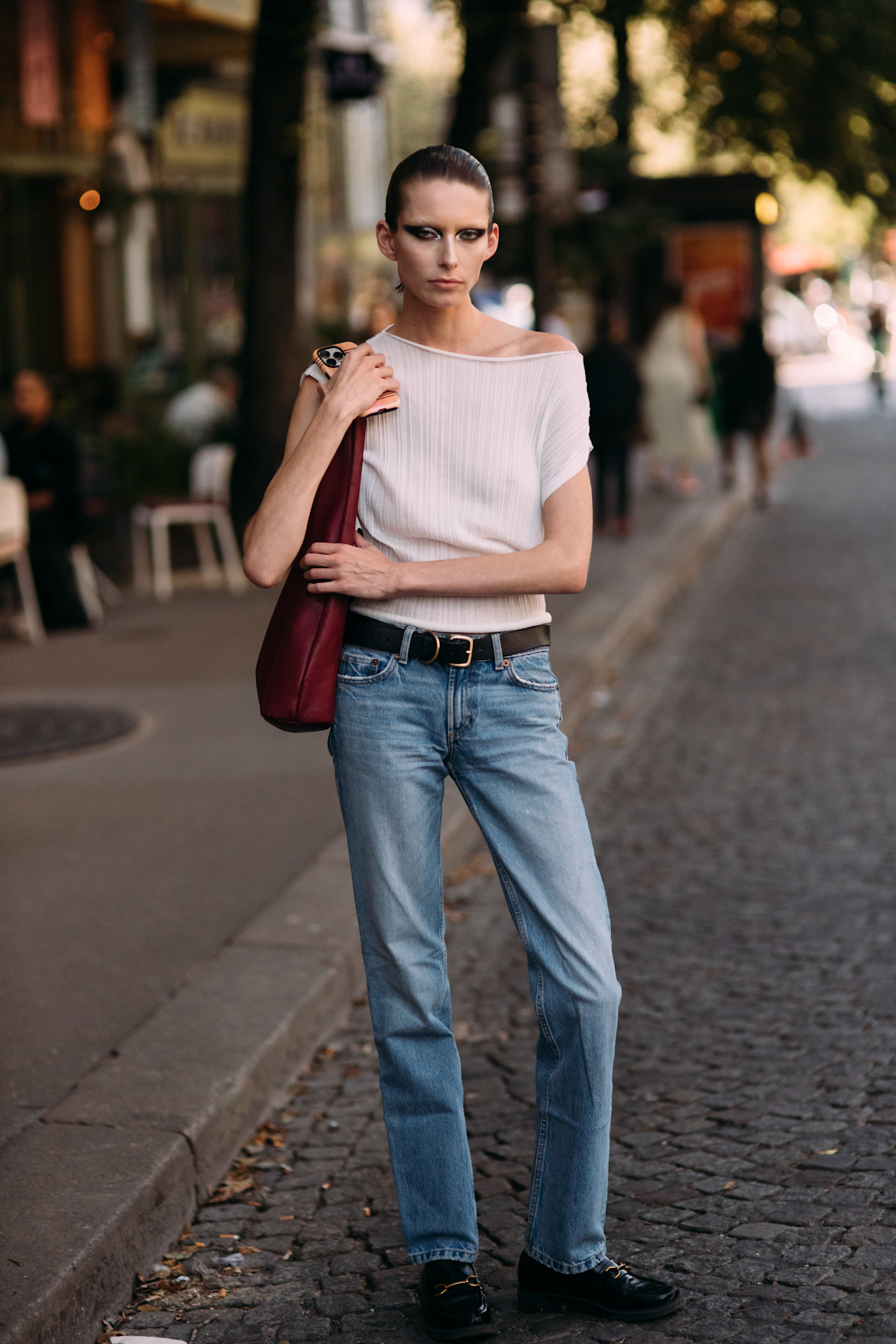 woman wears a knit top, blue jeans, and loafers