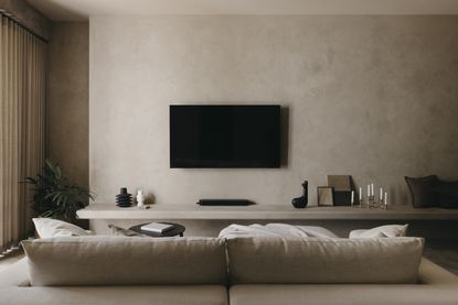 A living room with limewash walls, a TV on the wall and neutral-toned furniture