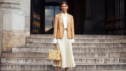 woman in white pleated skirt, blazer, and boots
