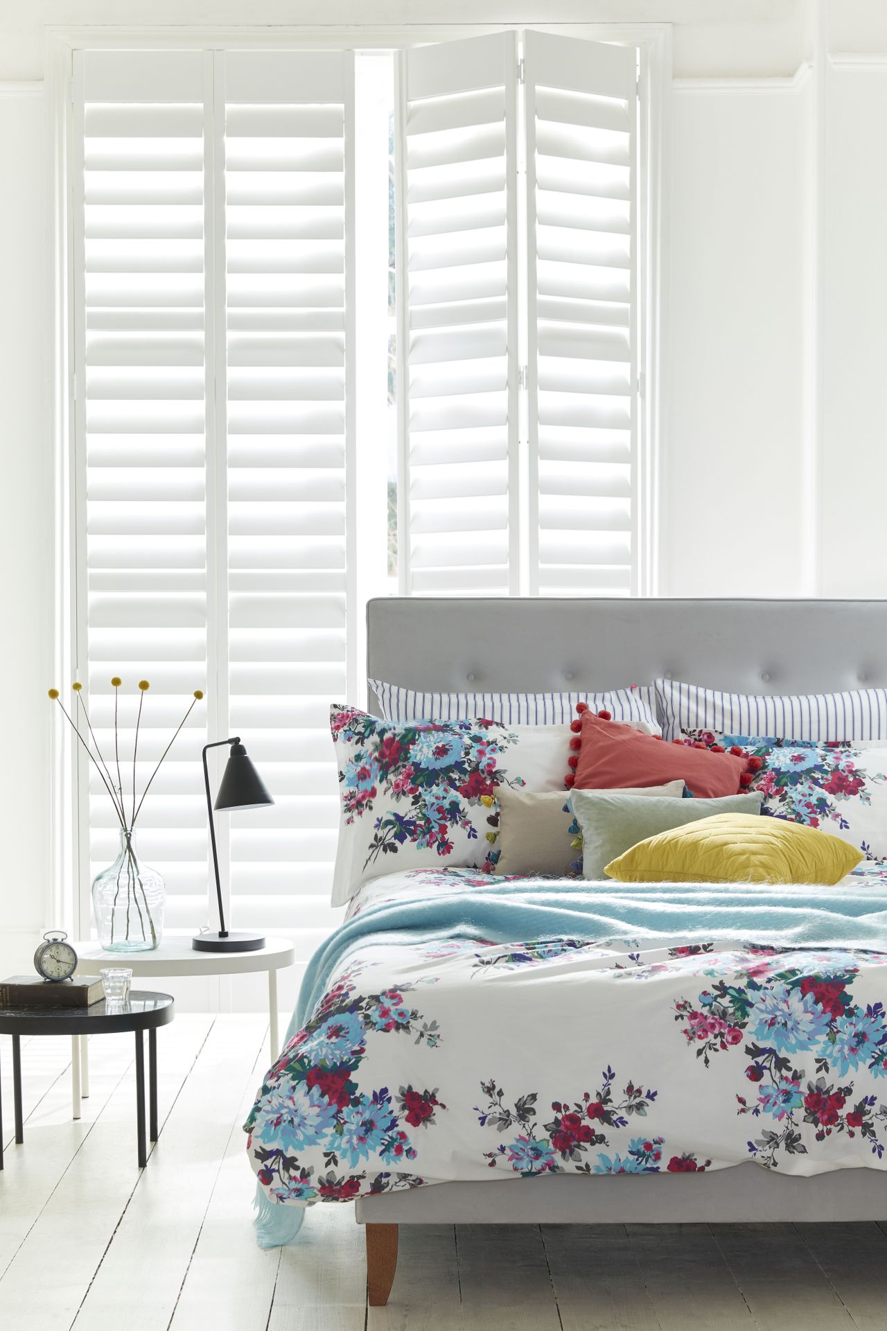 White bedroom with white shutters and bright patterned bedding