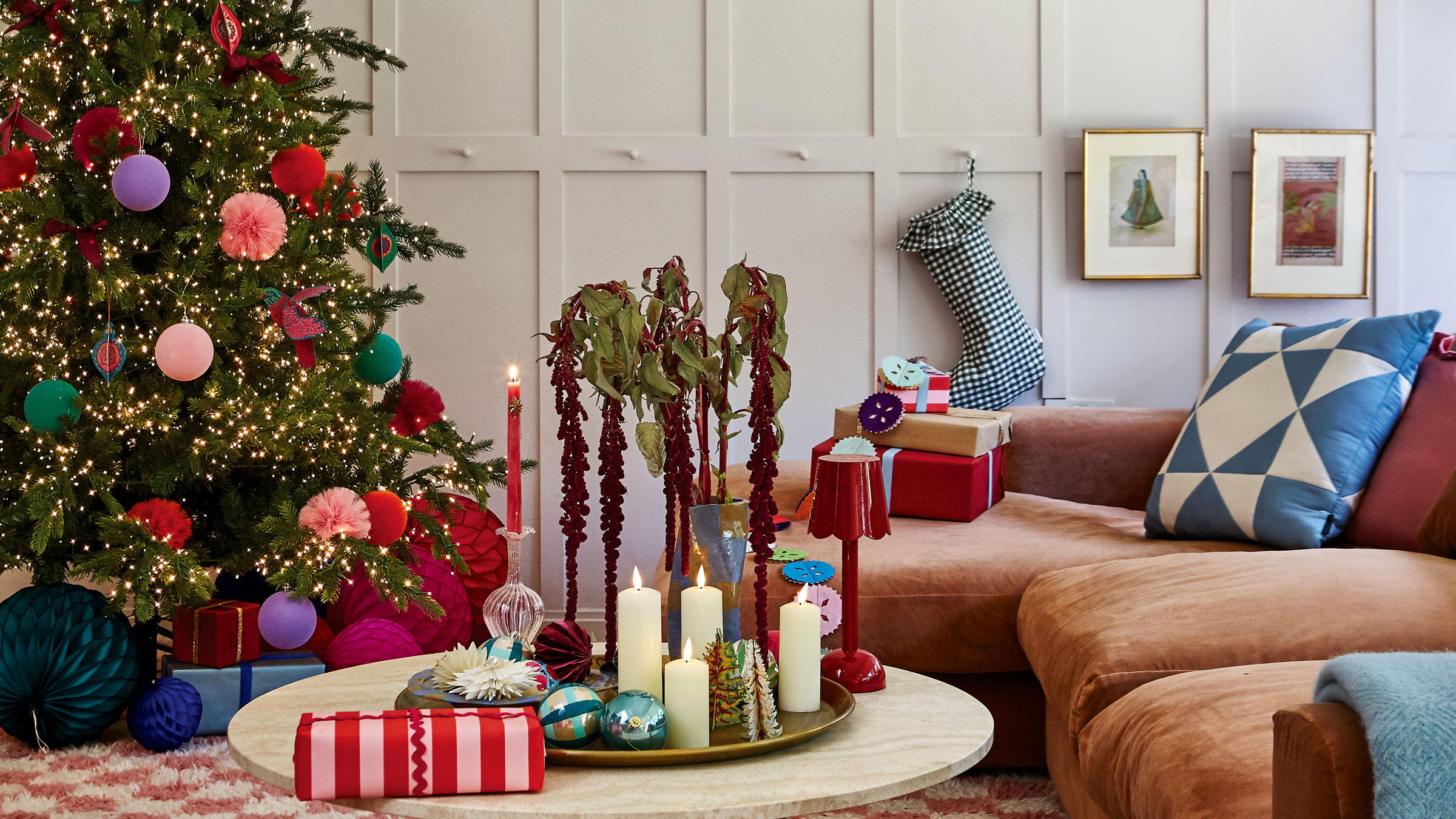 Christmas tree with paper decorations and pompoms, and a marble coffee table with brown sofa