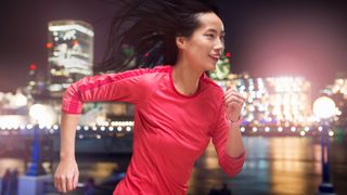 Young Asian woman running at night in the city