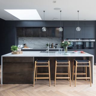 Kitchen with black cabinetry, wooden floors, large island and bar stools