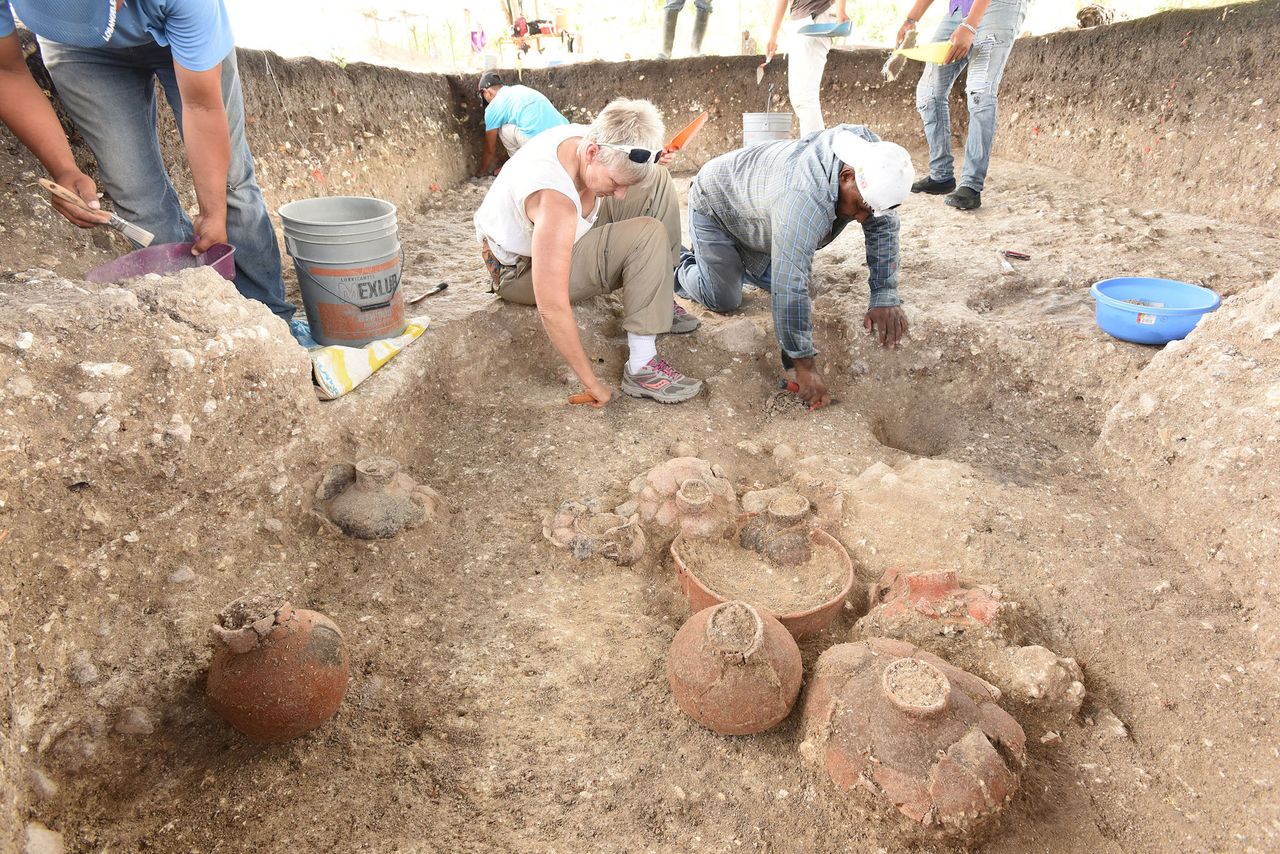 Study co-researcher Daniela Triadan, a professor of anthropology at the University of Arizona (center) excavates a cache at Aguada F&eacute;nix dating to 900-800 B.C. This cache contained multiple ceramic vessels.
