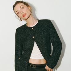 Reformation model wearing a black tweed jacket with a white, cropped tee and short black shorts.