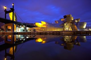 Spain, Bilbao, Guggenheim Museum and bridge, illuminated at dusk