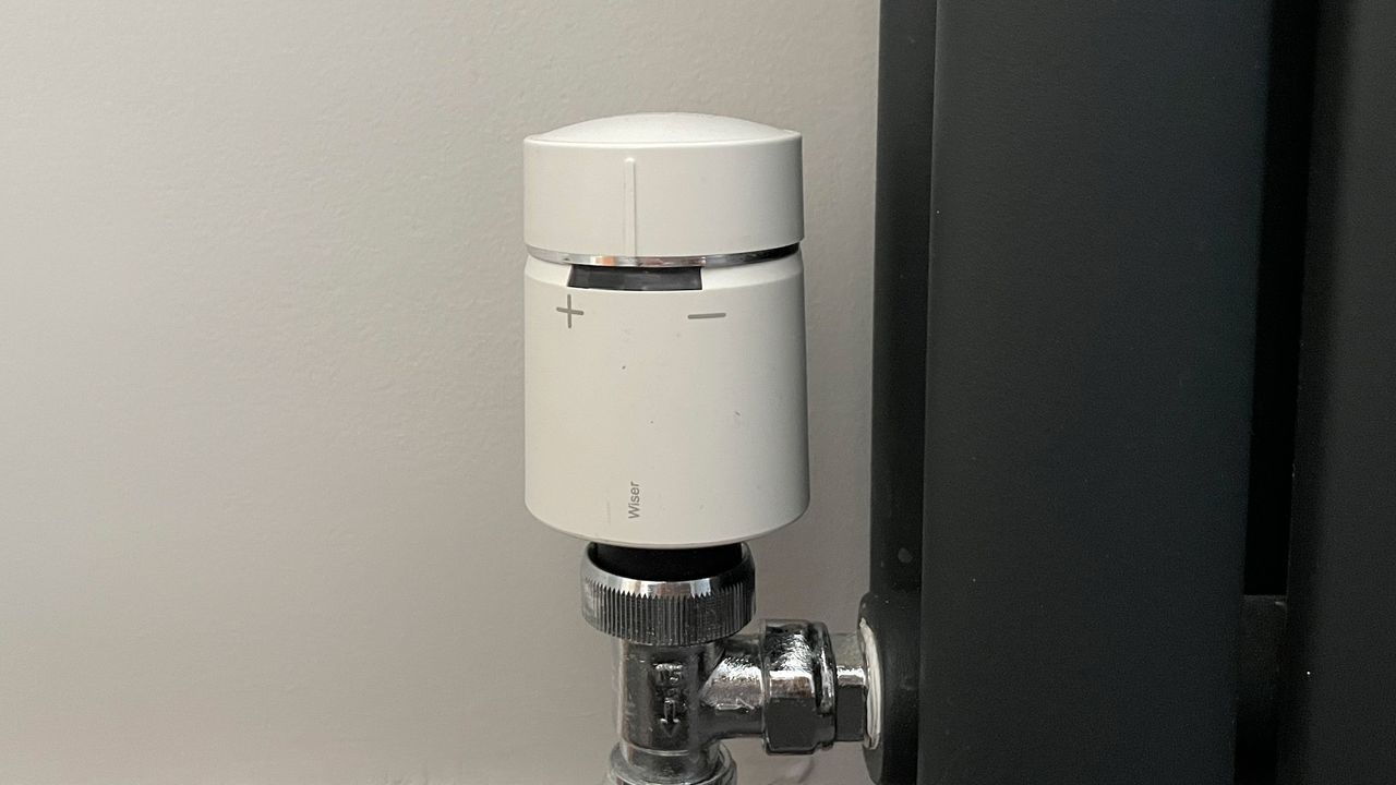 Radiator valve for Drayton Wiser Smart Thermostat, installed on a black radiator to illustrate its simple temperature up and down controls
