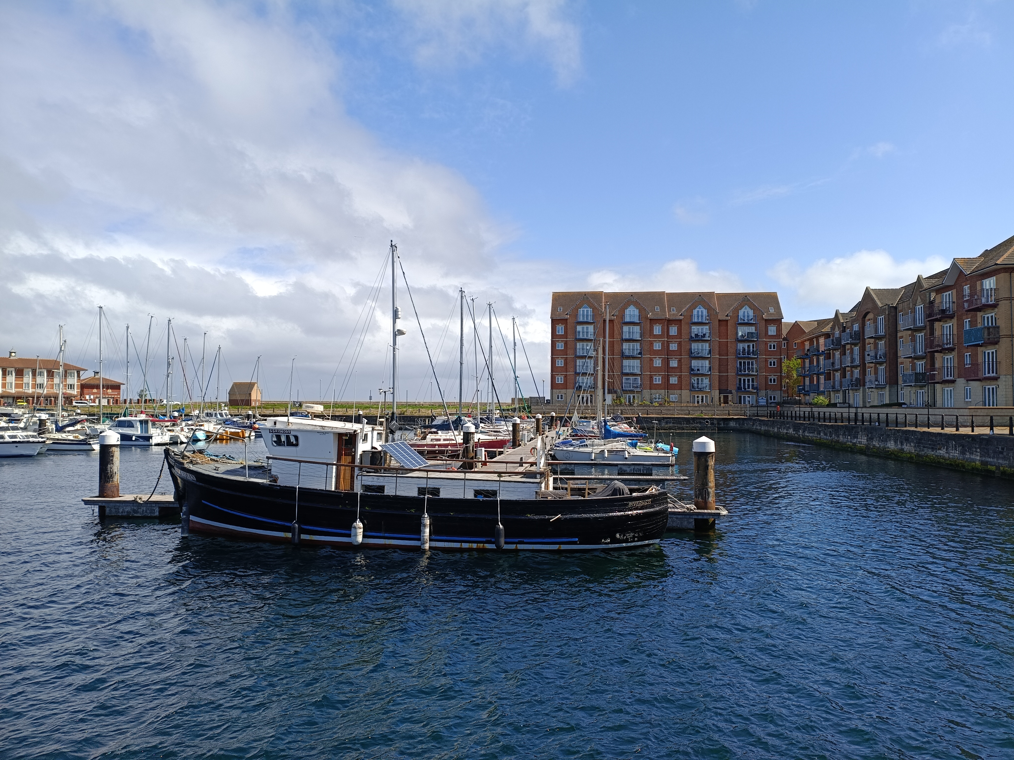 A marina scene with boats moored in calm water on a sunny day