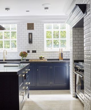 A kitchen entirely covered in white subway tiles, with dark blue cabinetry and a kitchen island.