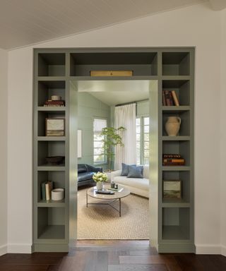 entry to library with cream walls, green built-in unit around door and herringbone floor