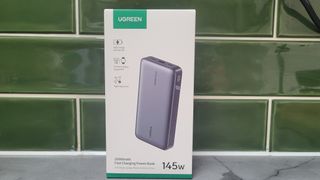 The Ugreen power bank packaging in front of a tiled wall.