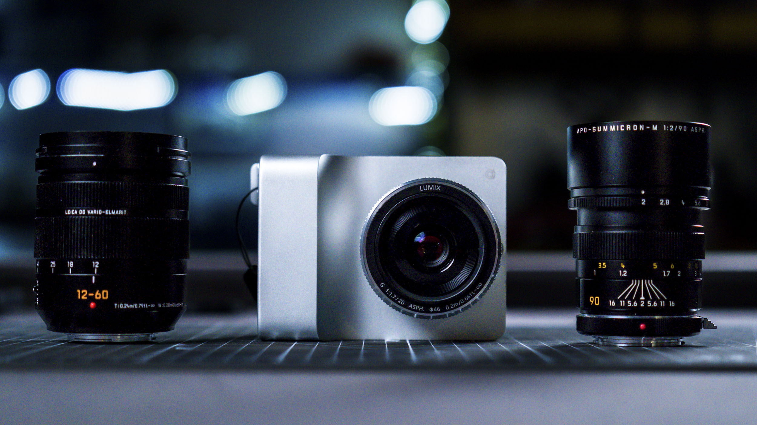 Caira camera on a grid mat alongside Lumix lenses