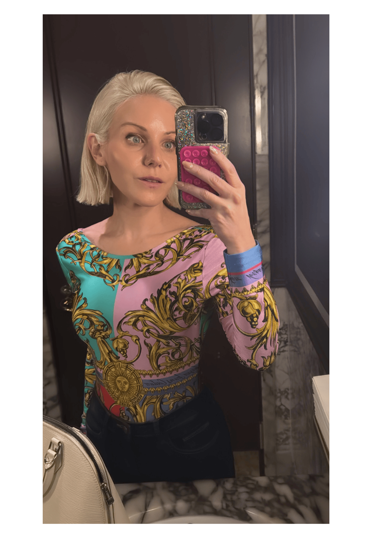 Micaela English in a colorful top taking a mirror selfie