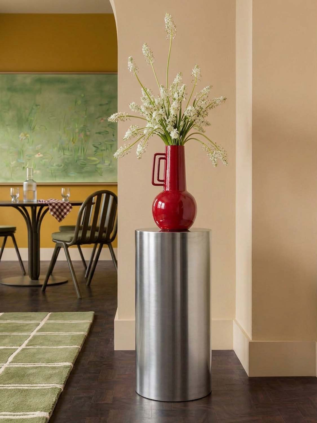 A steel round side table with a red vase on top
