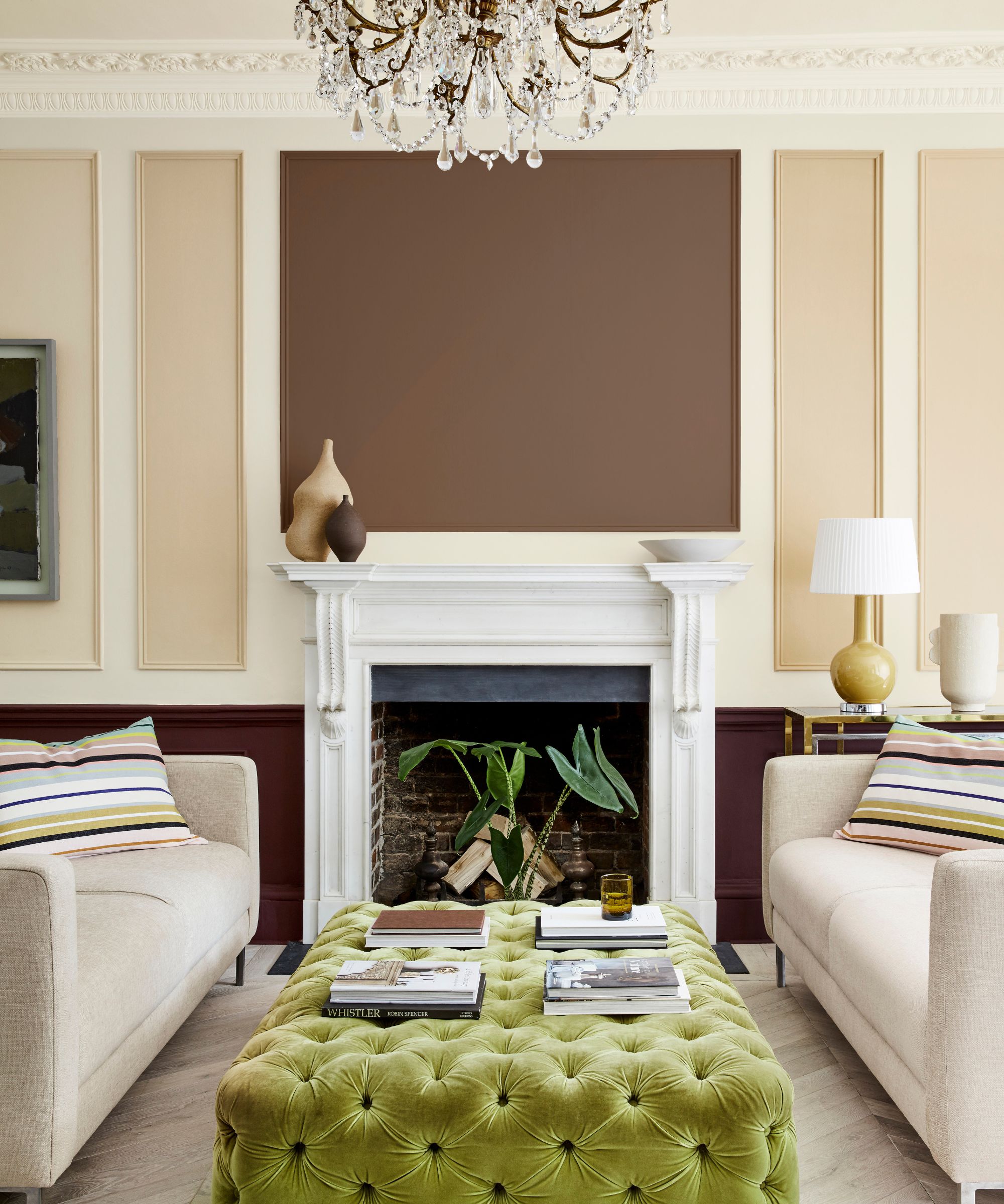 living room with beige panelled walls, two gray sofas and a green ottoman