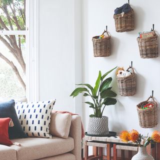 A family living room with a beige sofa with colourful cushions and a basket toy storage fixed to the wall