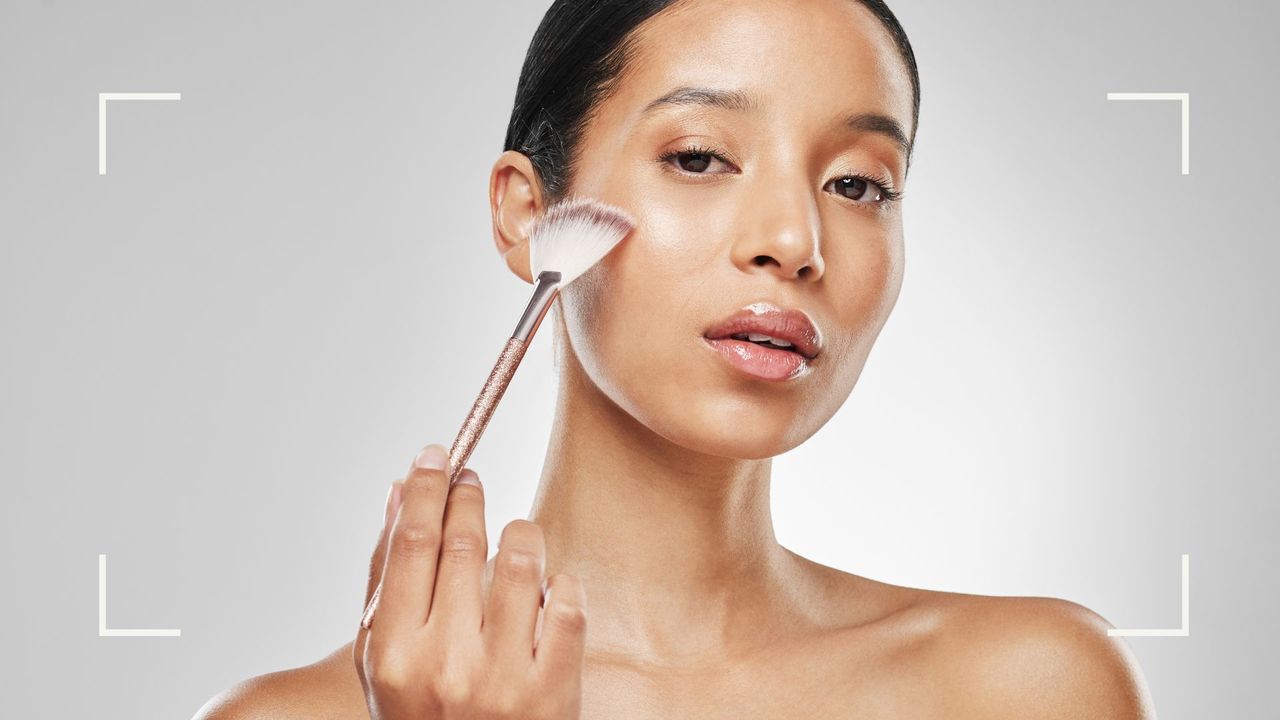 A headshot of a woman holding a bronzer brush, showing how tantouring can transform your face and body