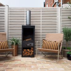 outdoor patio with painted fence two chairs and a wood burner