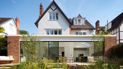 The exterior of a home with the view of the backyard and the outside of a kitchen extensions. There are large sliding patio doors that lead into the kitchen