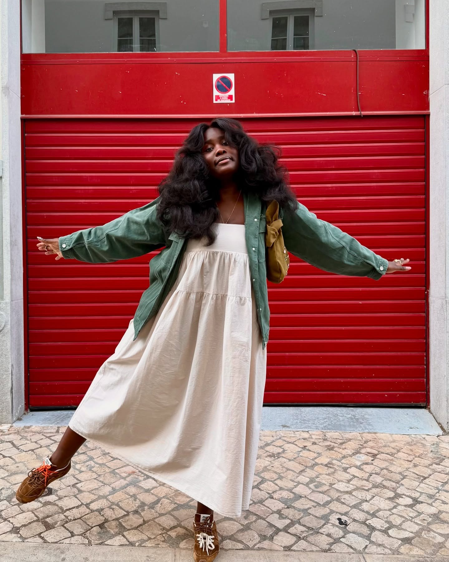 Fashion Person Luena Gama wears a green denim jacket, beige maxi babydoll dress, Miu Miu X New Balance 530 SL suede sneakers and a Khaki green bag in a recent image taken from her Instagram.