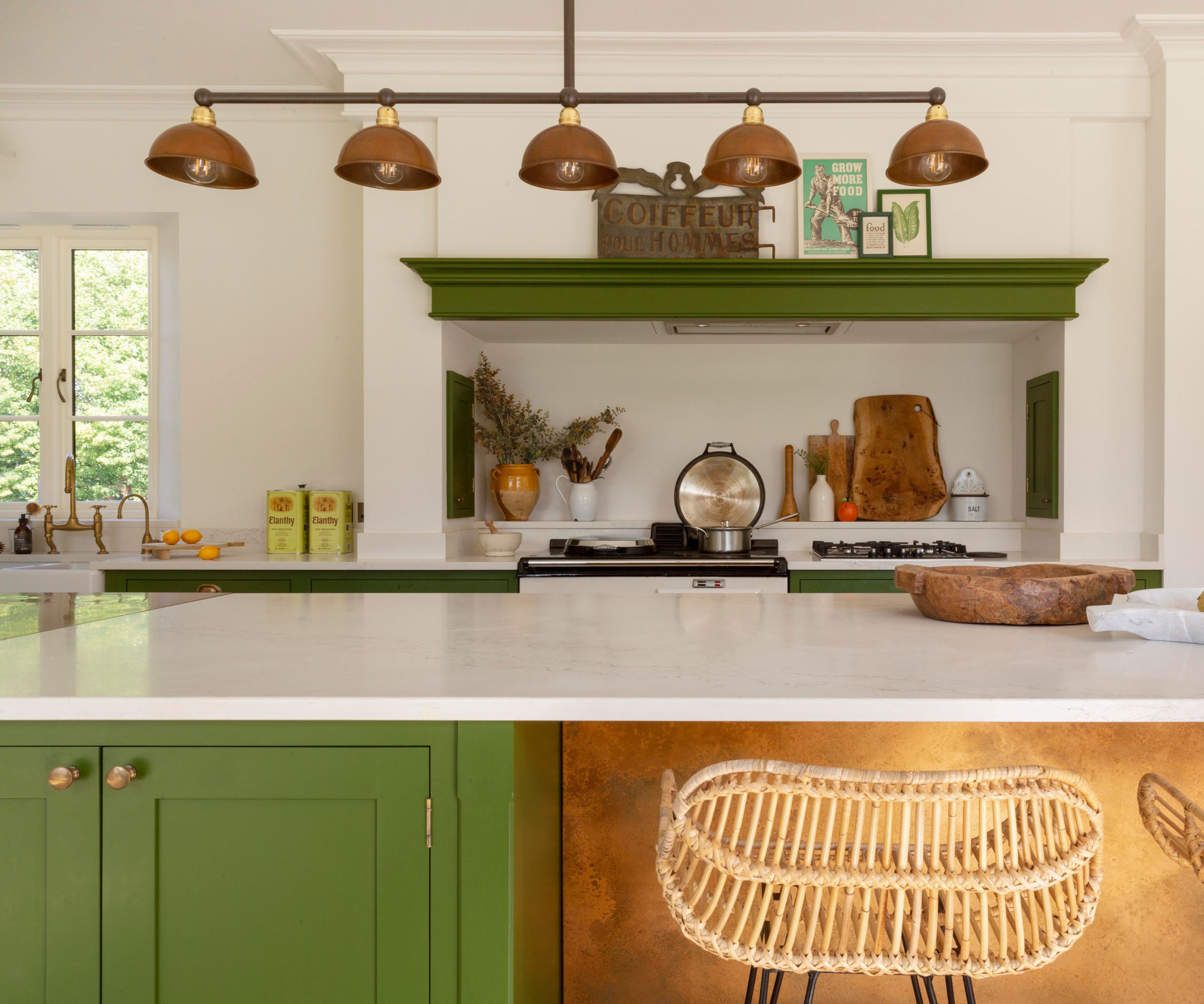 A green and white kitchen with a vintage brass light over the island