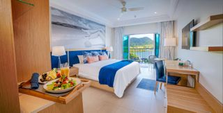 A white bedspread and blue blanket cover a bed at The Harbor Club in St. Lucia