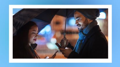 couple looking at their phones whilst standing under an umbrella in the rain, with a blue border around the image