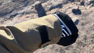 Closeup of man's arm in cycling glove and coat with muddy surface below
