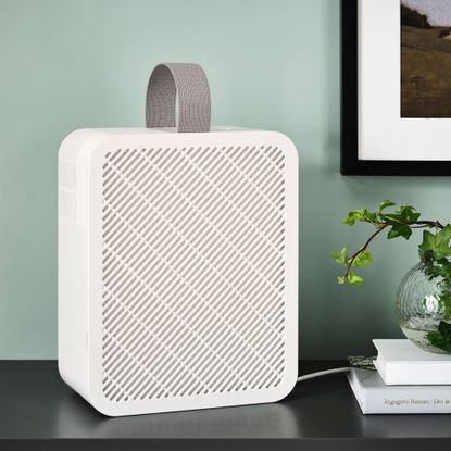 Ikea's UPPÅTVIND air purifier on a sideboard beside a pile of books, a vase and a framed picture