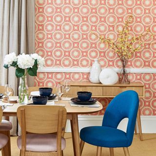 mid century modern dining room with dining table chairs and vibrant orange circular motif wallpaper