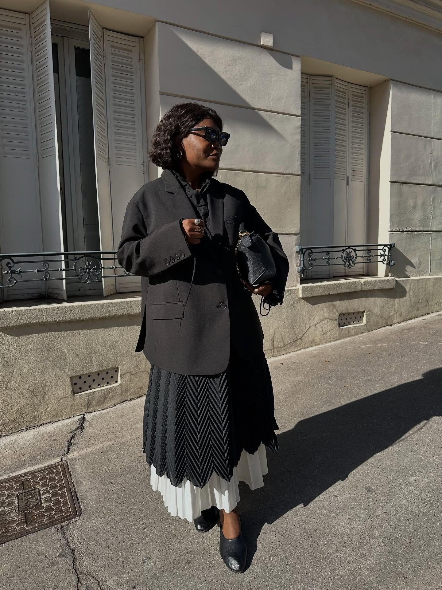 Frann Fyne wearing a skirt outfit idea for 2026, including a black blazer and plissé skirt.