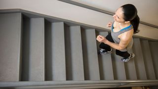 Woman running up stairs in workout clothes after a run, smiling