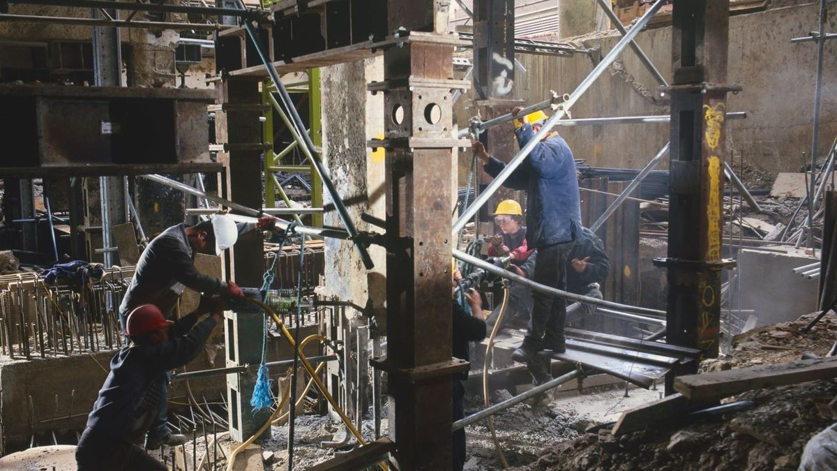 Builders underpinning a house