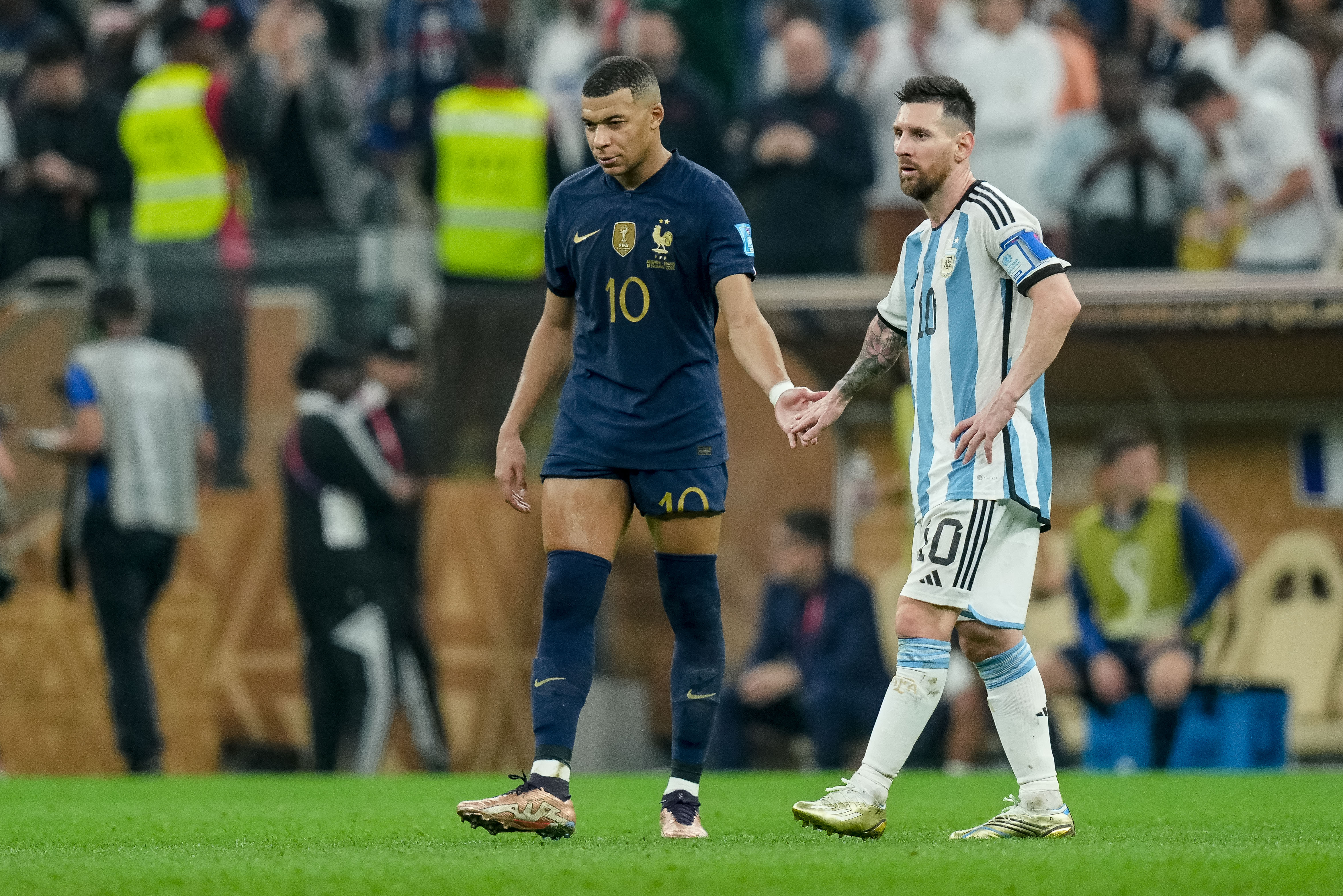 Kylian Mbappé and Lionel Messi shake hands during the 2022 World Cup final in Qatar.