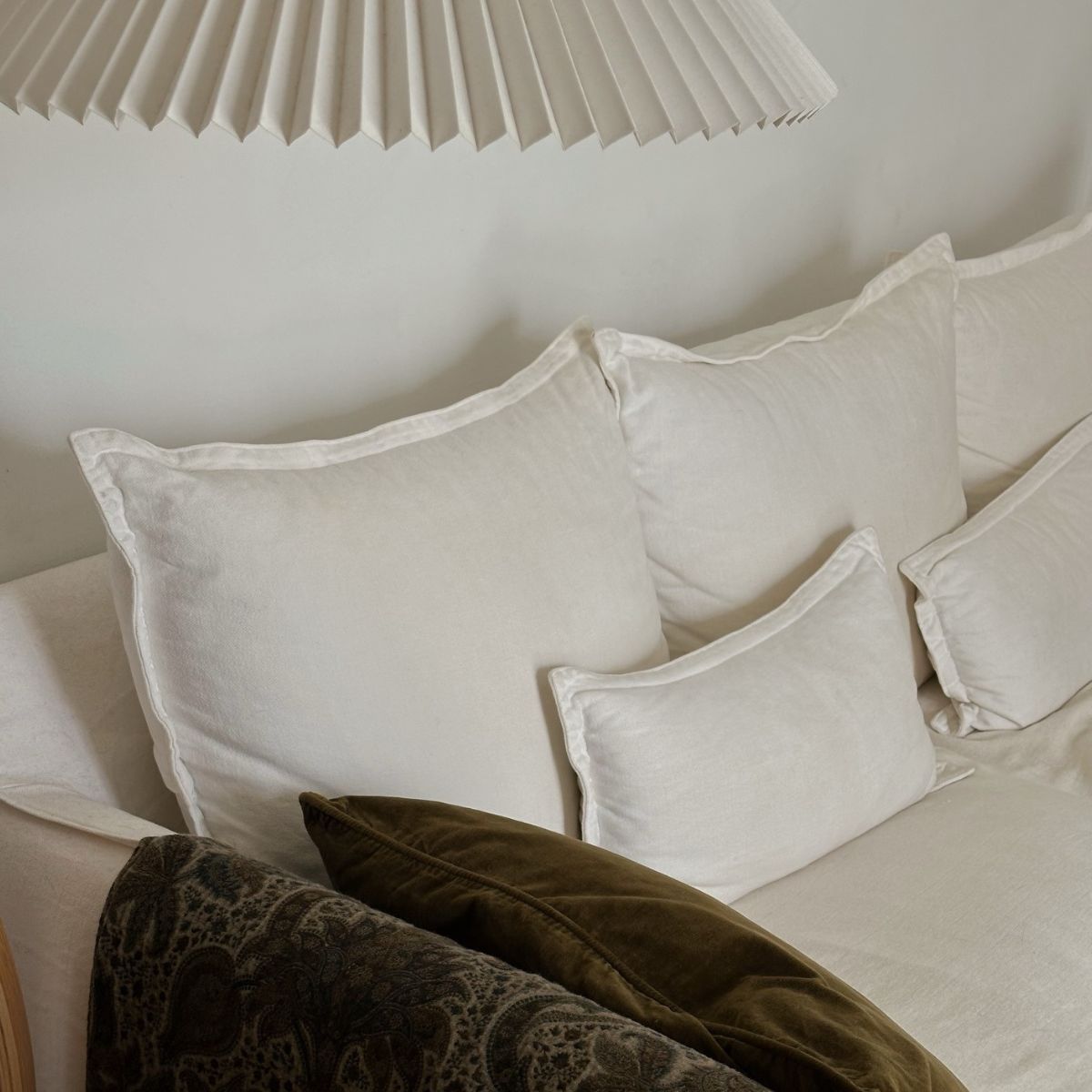 A chic cream sofa with a dark green throw and pillow