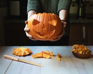 woman holding carved Halloween pumpkin